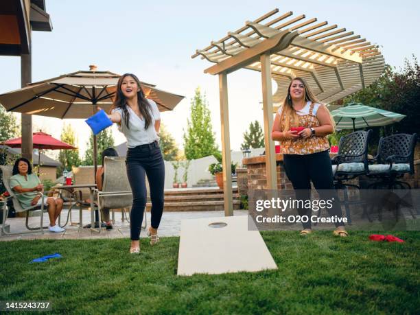 backyard party playing cornhole bean bag toss game - playing corn hole stock pictures, royalty-free photos & images