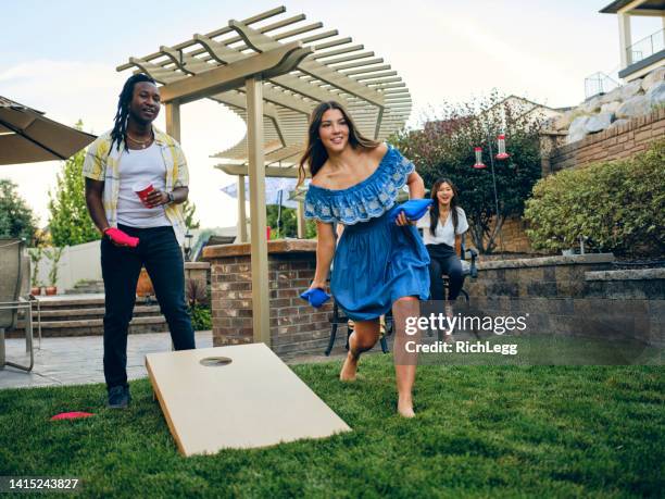 backyard party playing cornhole bean bag toss game - match of friendship stock pictures, royalty-free photos & images