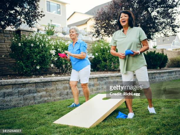 backyard party playing cornhole bean bag toss game - corn hole stock pictures, royalty-free photos & images