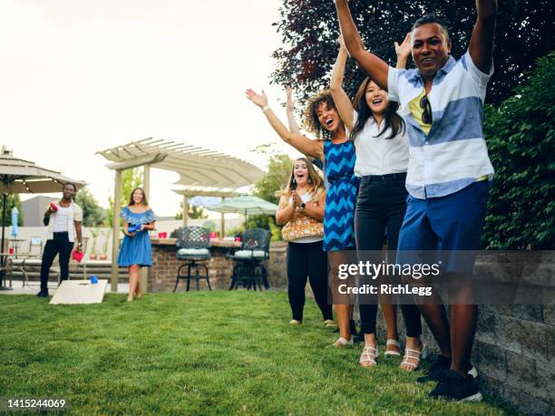 backyard party playing cornhole bean bag toss game - corn hole stock pictures, royalty-free photos & images