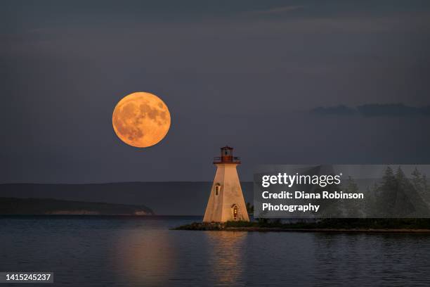 the july supermoon rises near the kidston island lighthouse on kidston island, located in the bras d'or lakes in baddeck, nova scotia, canada - super moon stock pictures, royalty-free photos & images