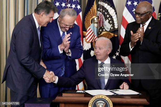 President Joe Biden shakes hands with Sen. Joe Manchin after signing The Inflation Reduction Act with Senate Majority Leader Charles Schumer and...