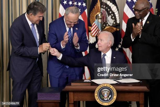 President Joe Biden gives Sen. Joe Manchin the pen he used to sign The Inflation Reduction Act with Senate Majority Leader Charles Schumer and House...