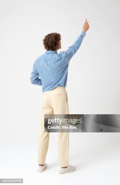 man reaching up as if interacting with a touch screen - touching fotografías e imágenes de stock