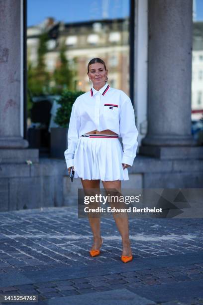 Guest wears gold earrings from Chanel, a white with navy blue and red striped print pattern on the borders / cropped shirt from Miu Miu, matching...