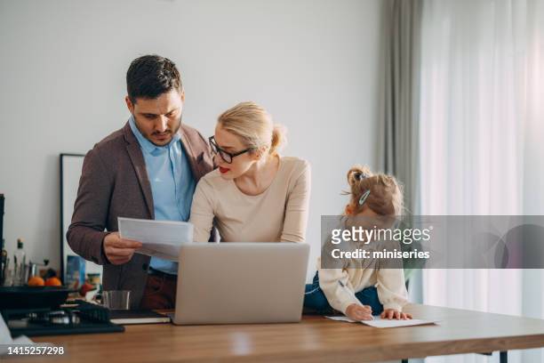 family finances: couple with a child looking at bills preparing to pay them online - energy bill stock pictures, royalty-free photos & images