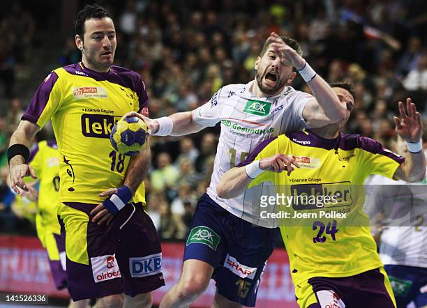 Guillaume Gille of Hamburg is challenged by Bartlomiej Jaszka and Iker Romero of Berlin during the EHF Champions League round of sixteen match...