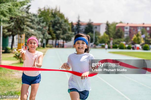 little girls crossing the finish line of a track race - relay race bildbanksfoton och bilder