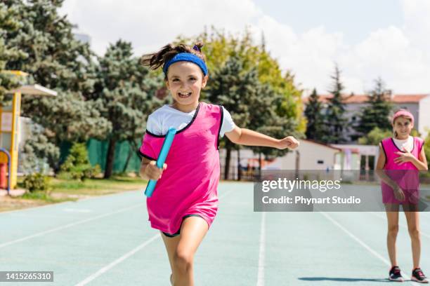kids passing the relay baton on the track field - stafett bildbanksfoton och bilder