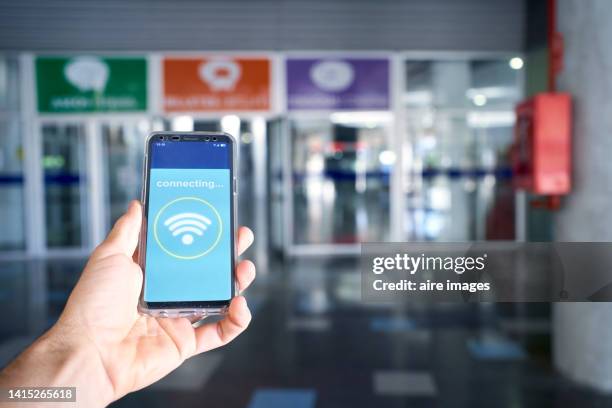 a person holding their phone that is connected to wifi in front of a glass door - slow internet stock pictures, royalty-free photos & images