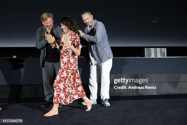 Justus von Dohnányi and producer Tom Spieß react as Iris Berben arrives with her shoes in her hands at the premiere of Der Nachname during the...