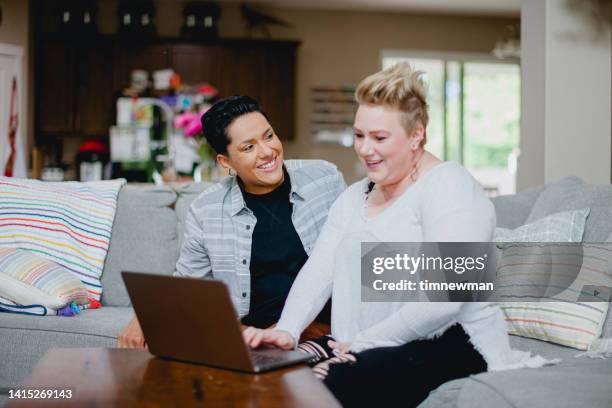 lesbian couple in their home using laptop - lesbian stock pictures, royalty-free photos & images