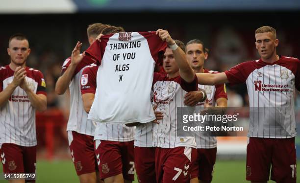 Sam Hoskins of Northampton Town celebrates after scoring his sides first goal by holding a shirt in honour of goalkeeper coach James Alger who's wife...