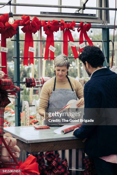 female shop owner wrapping gift for customer - christmas wrapping paper stockfoto's en -beelden