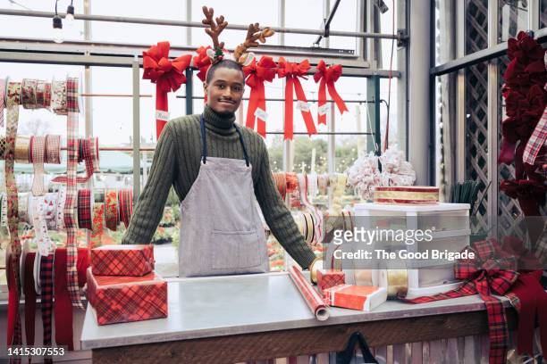 portrait of retail clerk wearing reindeer antlers at store - gift shop interior stock pictures, royalty-free photos & images