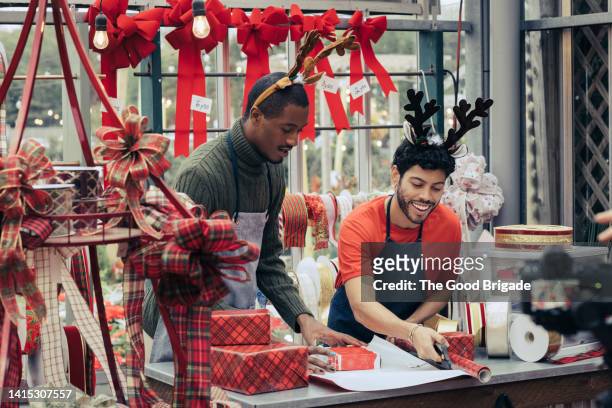 retail clerks wrapping gift in christmas decoration store - assistant foto e immagini stock