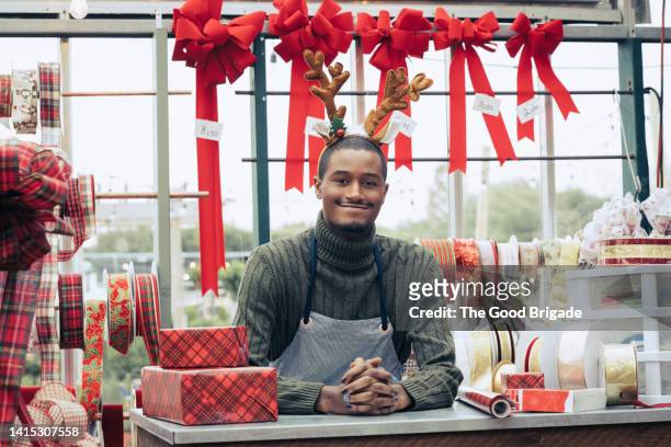 portrait of smiling shopkeeper during holiday season - christmas decorations in store foto e immagini stock