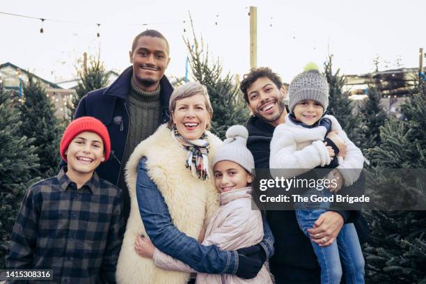 portrait of happy family standing at christmas tree farm - multi generation family christmas stock pictures, royalty-free photos & images