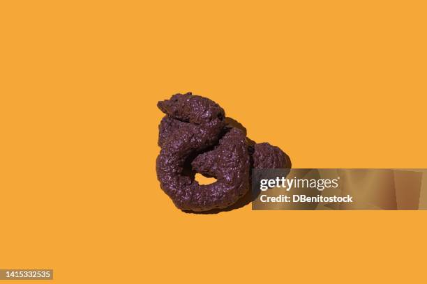 human or animal poop of brown color lying on yellow background. concept of defecate, poop, shit and prank. - cacca foto e immagini stock