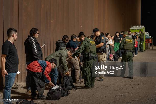 Border Patrol agents check for identification of immigrants as they wait to be processed by the U.S. Border Patrol after crossing the border from...
