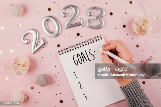 woman's hand writing goals 2023 for new year - new year's day stock pictures, royalty-free photos & images