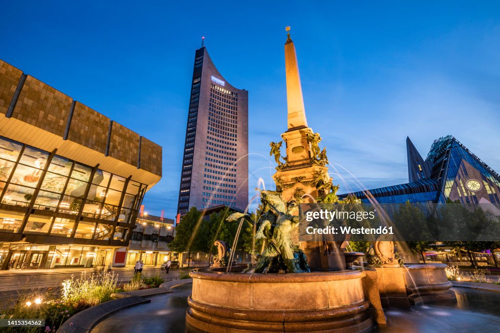 Germany, Saxony, Leipzig, Mendebrunnen fountain at dusk with City-Hochhaus, Gewandhaus and Paulinum in background