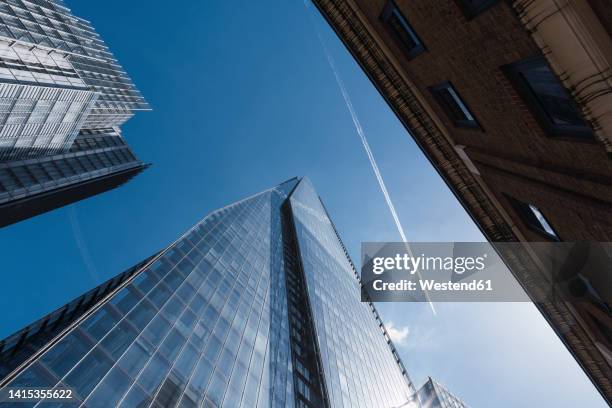 vapor trail over skyscrapers in city on sunny day - slipstream stock pictures, royalty-free photos & images