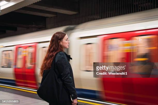 young woman standing in front of subway at platform - london tube stock pictures, royalty-free photos & images