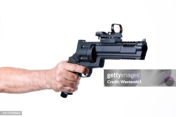 hand of man shooting with revolver against white background - hand holding gun stock pictures, royalty-free photos & images