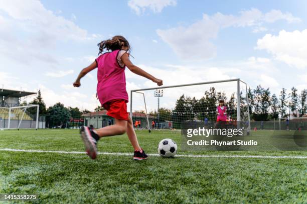 kids practicing penalty kicks and playing soccer. female goalkeeper playing football with friend - 女孩 個照片及圖片檔