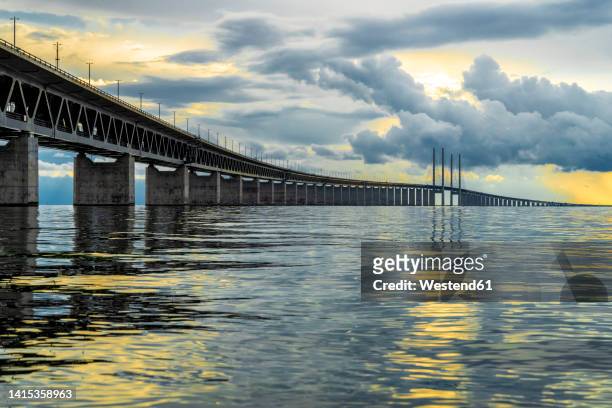denmark, copenhagen, clouds over oresund bridge at dusk - oresund bridge stock pictures, royalty-free photos & images