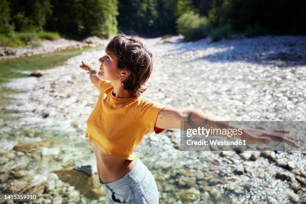 smiling woman standing with arms outstretched on sunny day - 容易 個照片及圖片檔