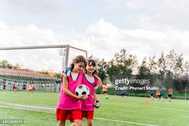 two soccer teammates walking off the field after a win - girls football stockfoto's en -beelden