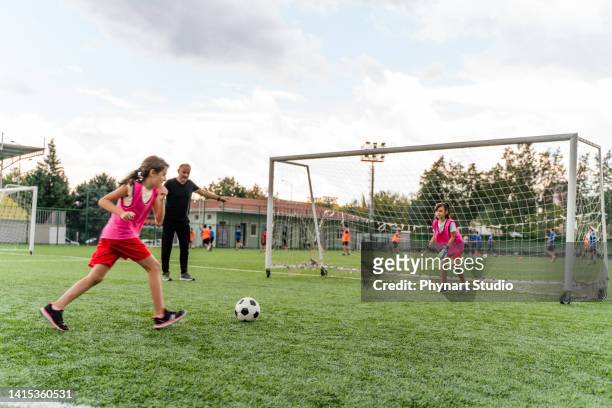 kids practicing penalty kicks and playing soccer. female goalkeeper playing football with friend - summer school imagens e fotografias de stock