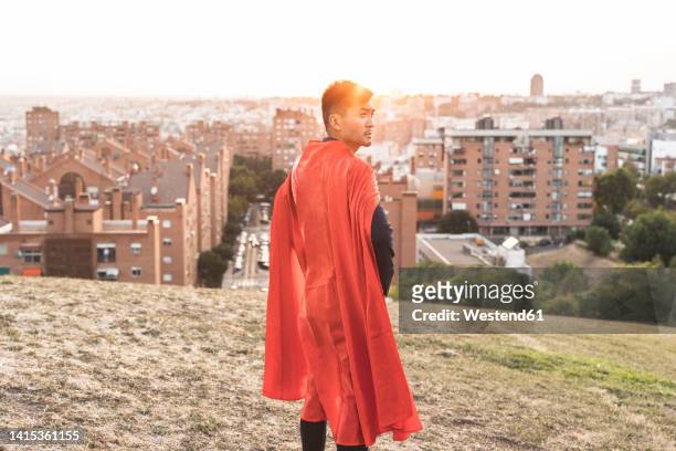 young businessman with red cape standing on top of hill - held madrid stock-fotos und bilder