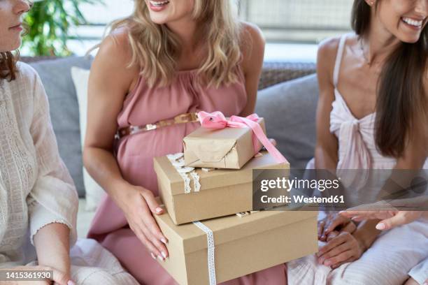 pregnant woman holding gift boxes by friends at baby shower - chá de bebé imagens e fotografias de stock