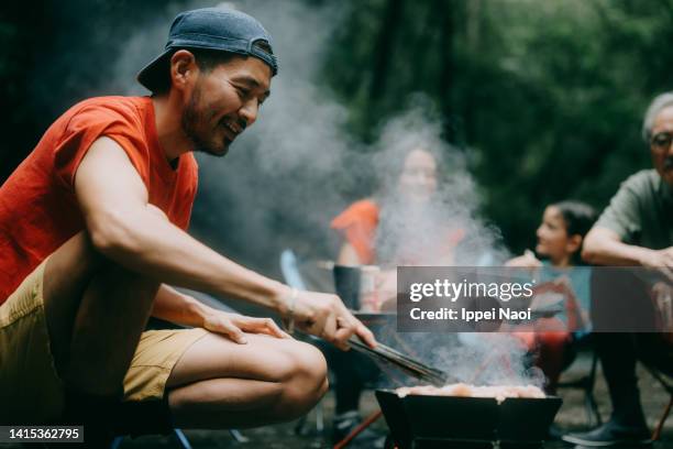 man enjoying bbq with family in nature - camping stove stockfoto's en -beelden