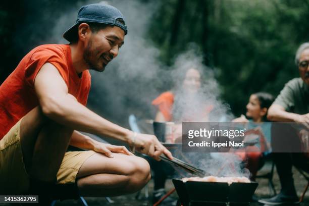 man enjoying bbq with family in nature - camping 個照片及圖片檔