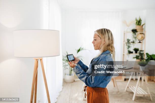 woman checking electrical consumption of lamp at home - domotic bildbanksfoton och bilder