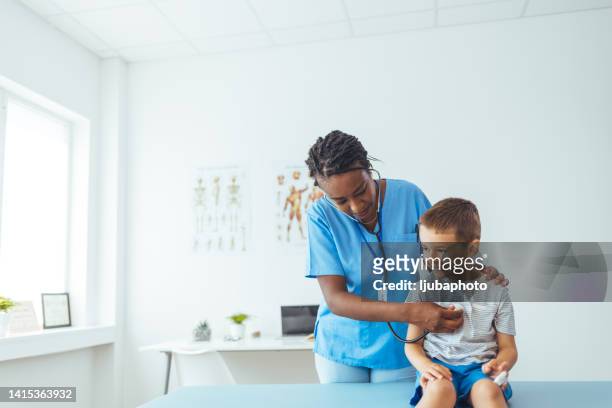 female doctor holds her stethoscope to her young patients chest as she listens to his heartbeat - listening to heartbeat 個照片及圖片檔