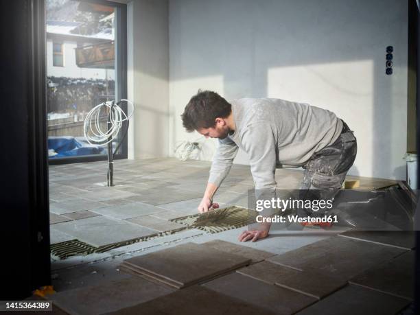 young tiler applying adhesive on floor at construction site - tiler stock pictures, royalty-free photos & images