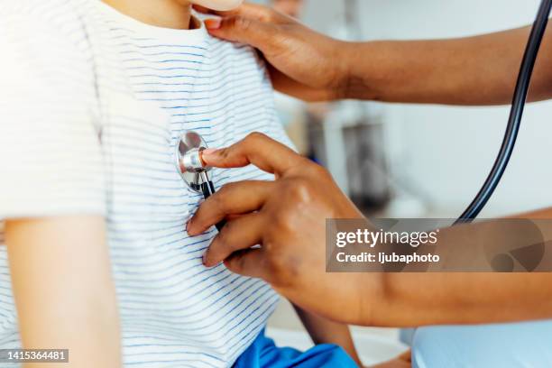 young female doctor examining a small boy in her office. - unrecognizable person stock pictures, royalty-free photos & images