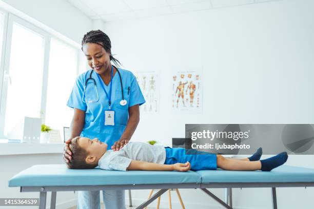 boy laying on back while his female doctor talking to him. - nurse listening to patient stock pictures, royalty-free photos & images