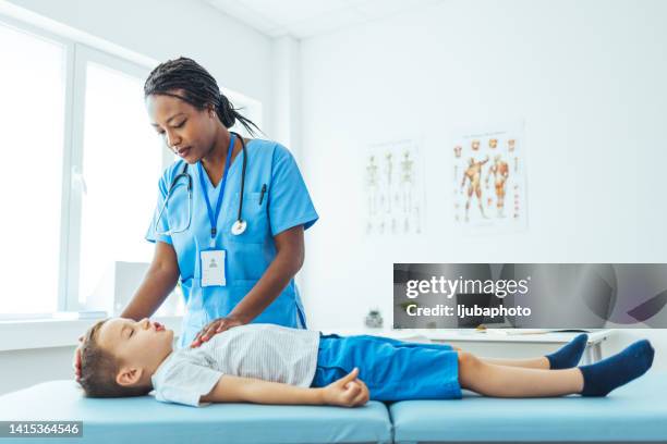 una dottoressa sta esaminando un ragazzo in una clinica medica - supino foto e immagini stock