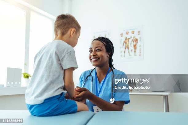 female doctor consoling her young patient and holding his hand - zuster stockfoto's en -beelden