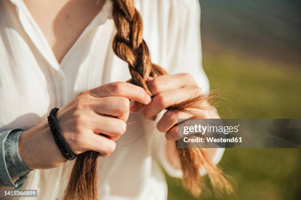 young woman braiding her hair - plat stock-fotos und bilder