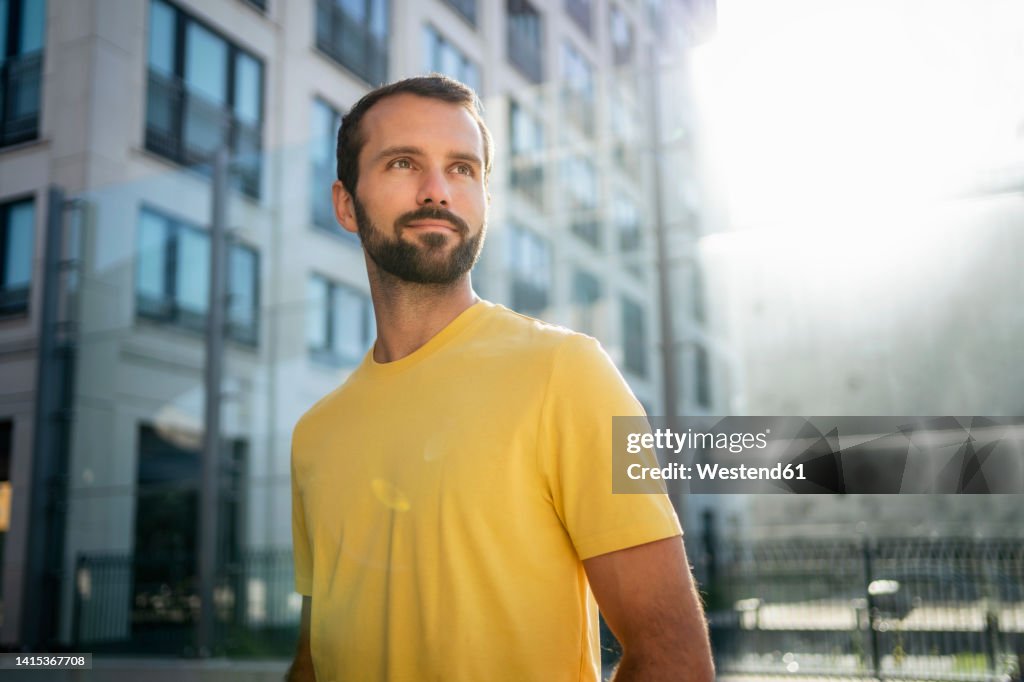 Smiling young man standing in front of building on sunny day