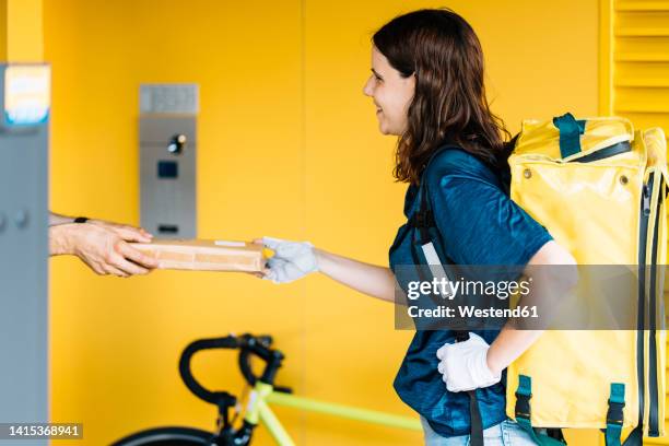 happy delivery woman giving package to customer - bike messenger stock-fotos und bilder