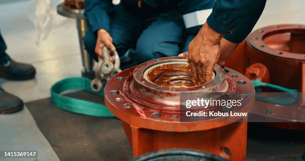 mecánico masculino engrasando una pieza de máquina metálica en el taller y fijando un mecanismo de transmisión de par. handyman recubre o usa lubricación en un engranaje de acero o dispositivo mecánico - lubricación fotografías e imágenes de stock