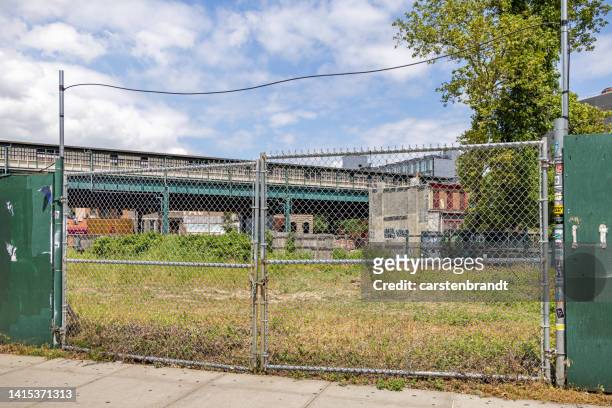 empty building site behind a gate and a elevated railway behind - chain link stock pictures, royalty-free photos & images